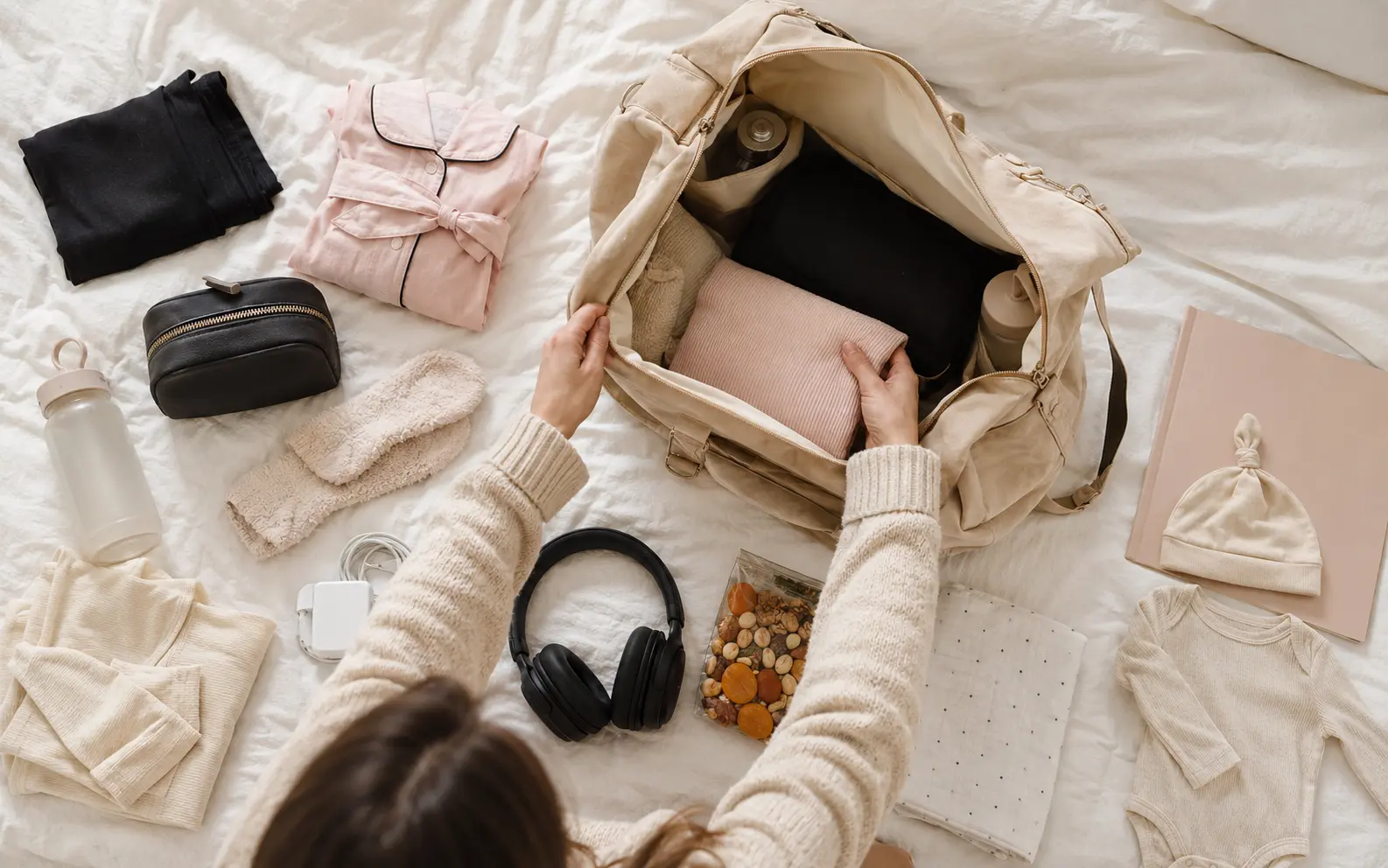 Geöffnete Kliniktasche mit geordneten Kleidungsstücken und Babybedarf