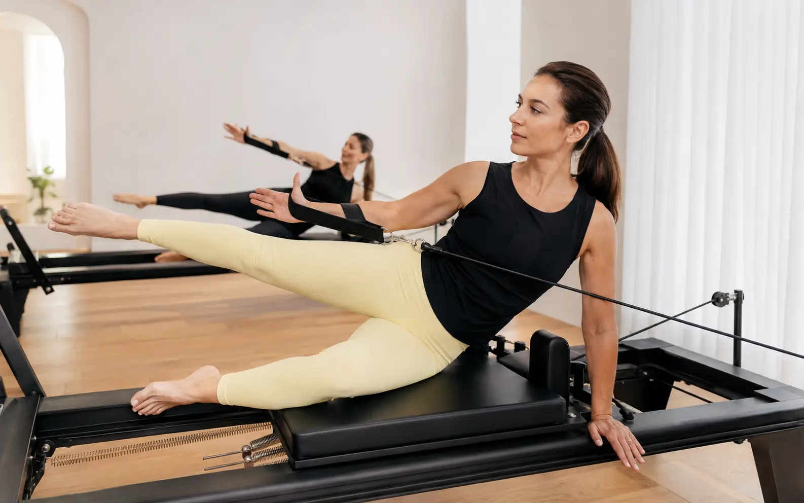 Zwei Frauen trainieren kontrolliert auf Pilates Reformern
